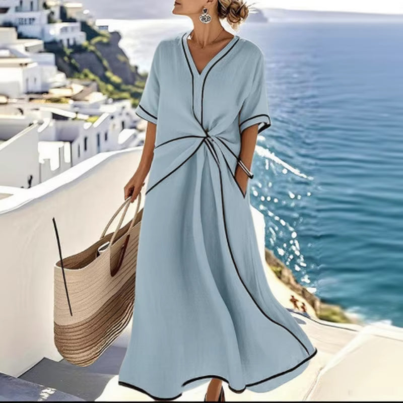 Woman wearing light-blue, black-trimmed A-line midi dress with twist-front, V-neck and short sleeves