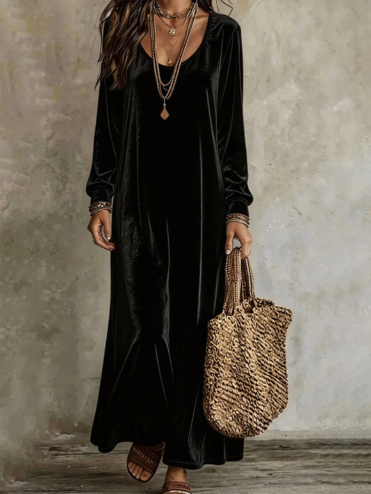 Model wearing a black velvet maxi dress with long sleeves, a round neckline, and a relaxed fit.
