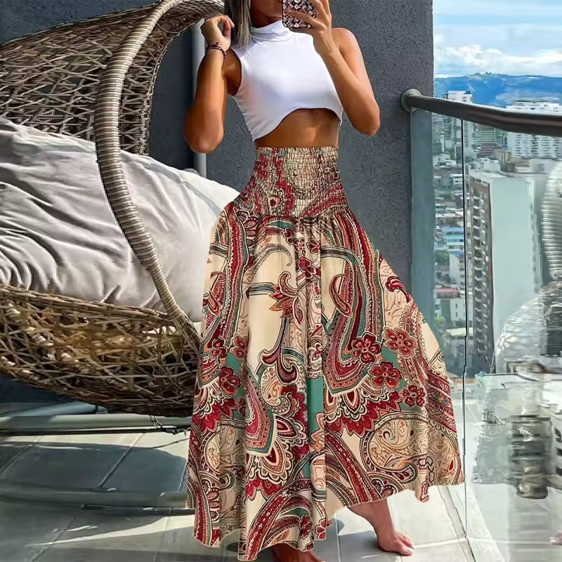 Woman wearing white crop top and A-line paisley print maxi skirt in red, beige, and teal with smocked waist