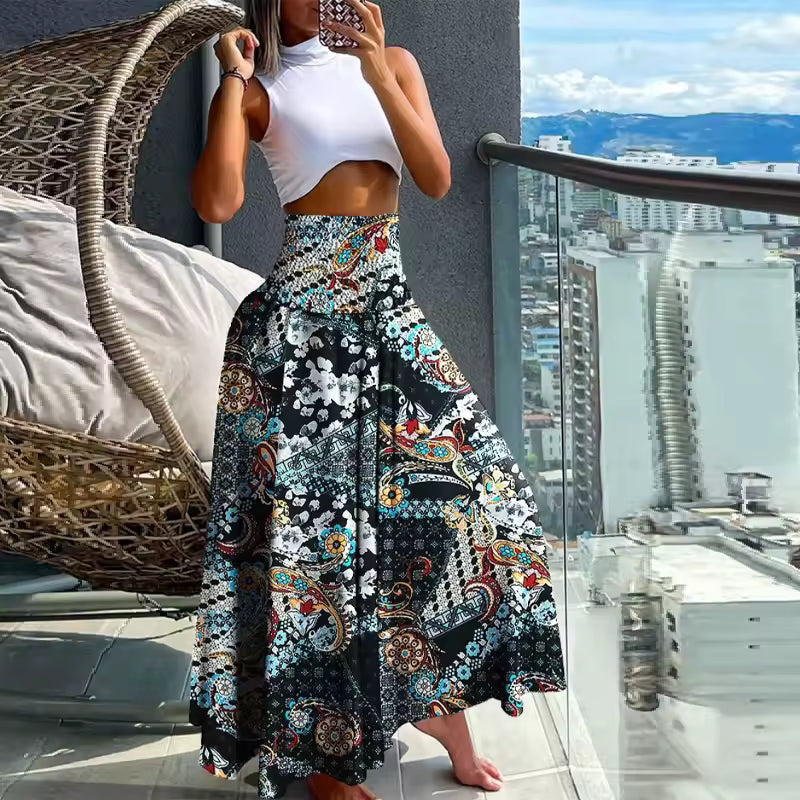 Woman wearing white crop top and A-line patchwork print maxi skirt in black, teal, and red with smocked waist