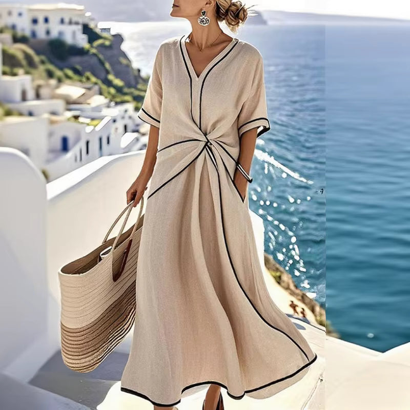 Woman wearing beige, black-trimmed A-line midi dress with twist-front, V-neck and short sleeves