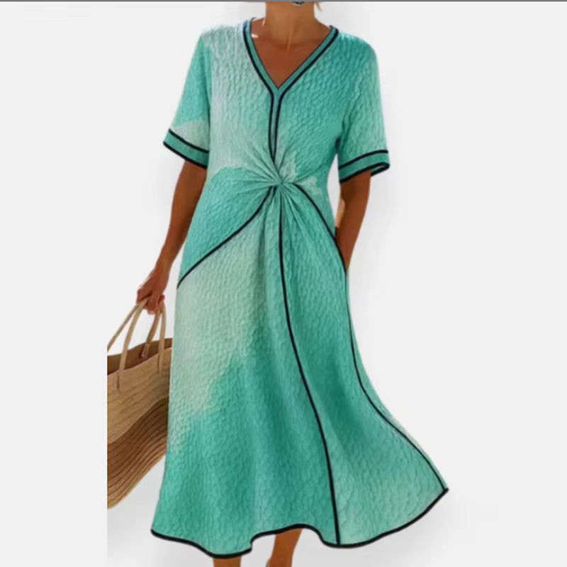 Woman wearing mint green, black-trimmed A-line midi dress with twist-front, V-neck and short sleeves