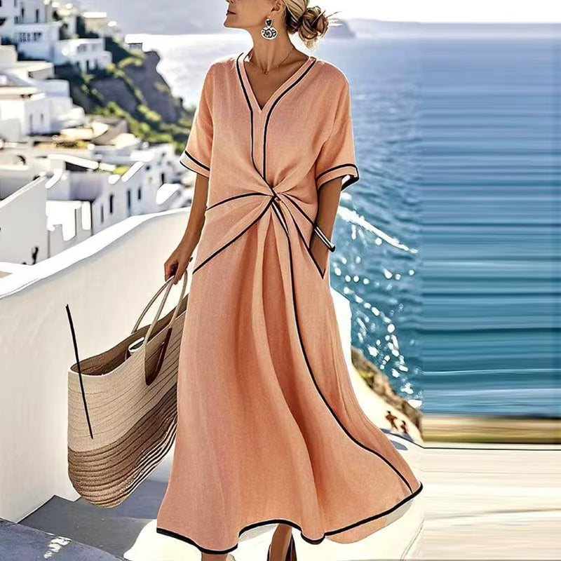 Woman wearing peach, black-trimmed A-line midi dress with twist-front, V-neck and short sleeves