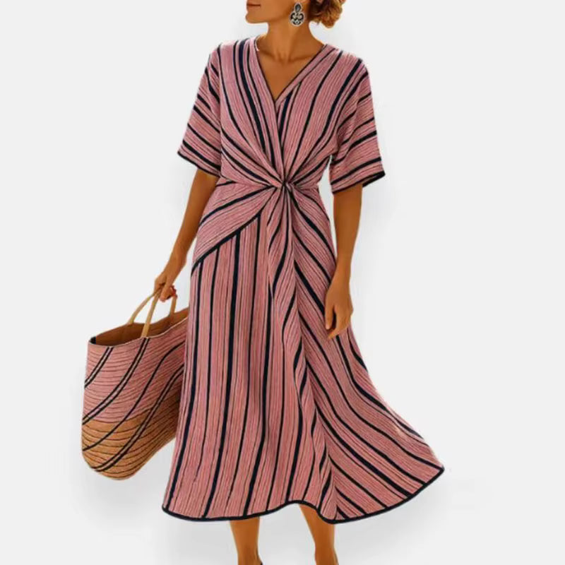 Woman wearing pink and navy striped A-line midi dress with twist-front, V-neck and short sleeves
