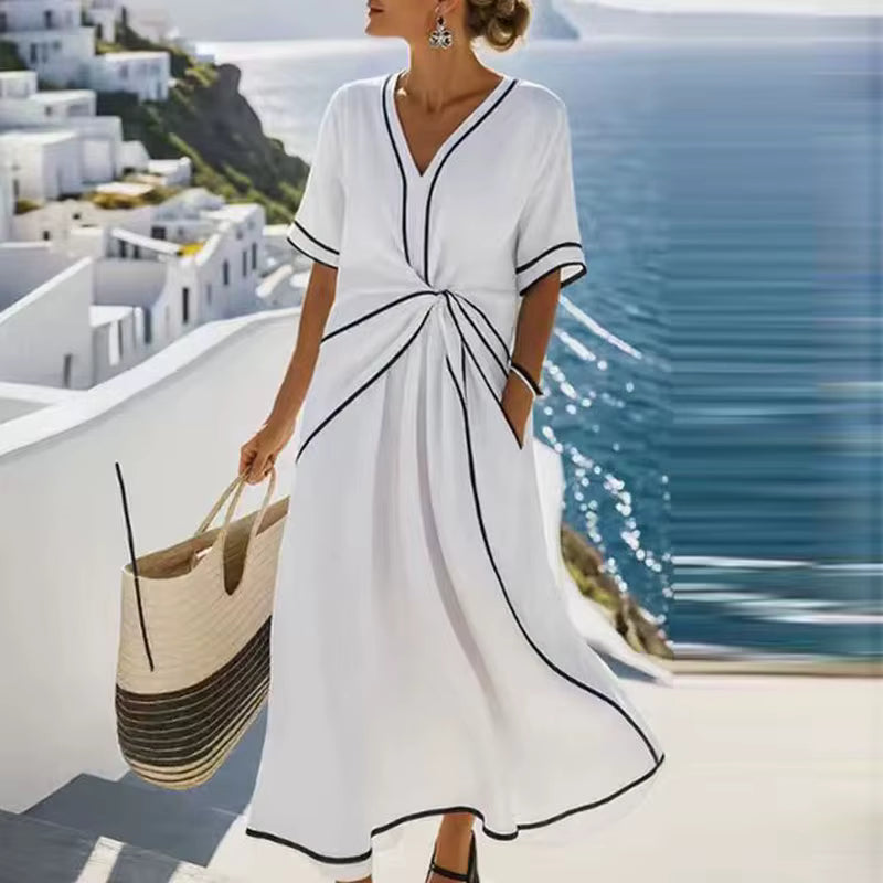 Woman wearing white, black-trimmed A-line maxi dress with twist-front, V-neck and short sleeves